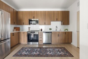 Une cuisine moderne avec des meubles en bois, des appareils en acier inoxydable et un tapis à motifs.