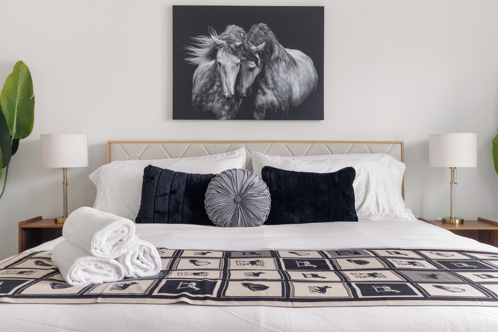 A neatly made bed with a patterned bedspread, two bedside lamps, and a framed artwork above.
