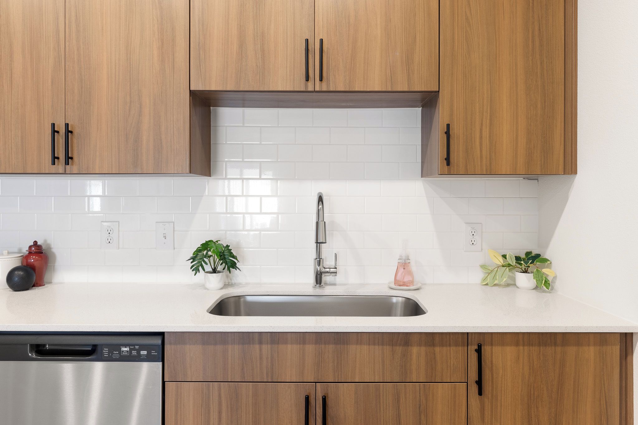 A kitchen with wooden cabinets, a stainless steel sink, and a dishwasher.
