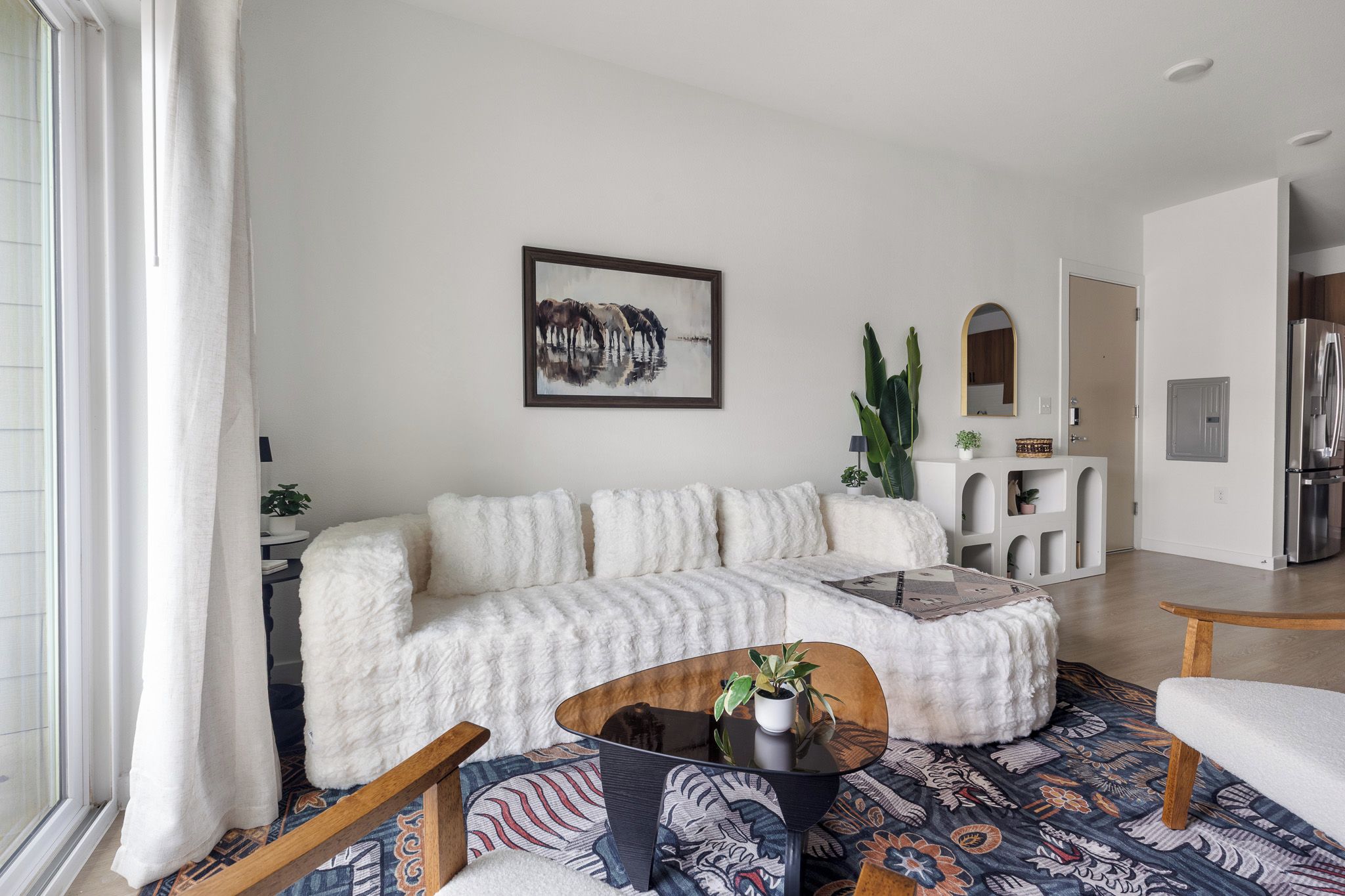 A modern living room with a white sofa, a coffee table, and a patterned rug.