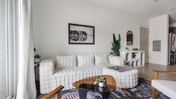 A modern living room with a white sofa, a coffee table, and a patterned rug.