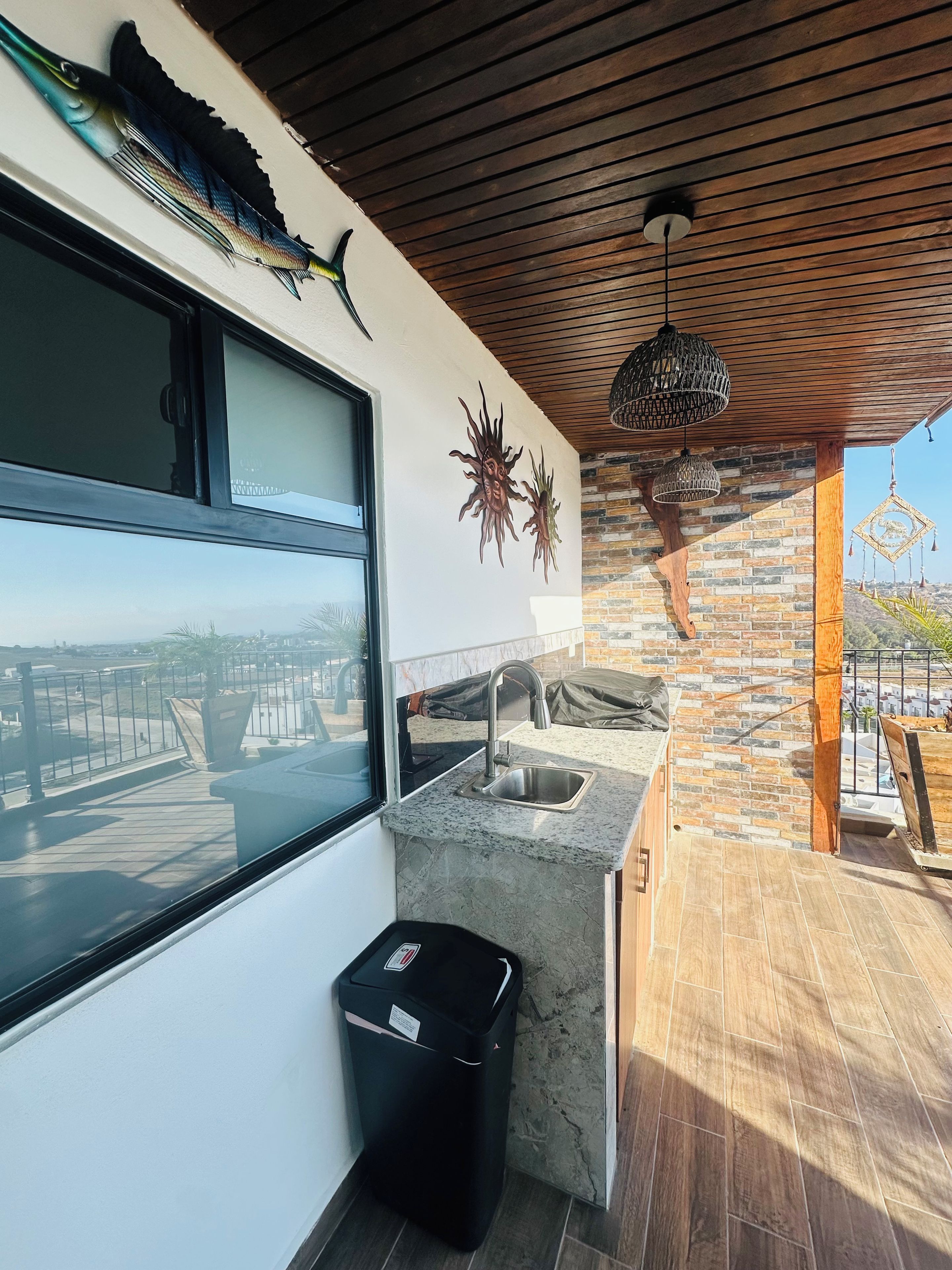 A modern kitchen with a large window, a stone backsplash, and a view of the cityscape.