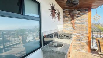 A modern kitchen with a large window, a stone backsplash, and a view of the cityscape.