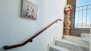 A staircase with marble steps and a wooden handrail, flanked by two framed pictures on the wall.