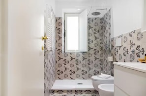 Ein Badezimmer mit Toilette, Waschbecken, Dusche und einem Fenster.