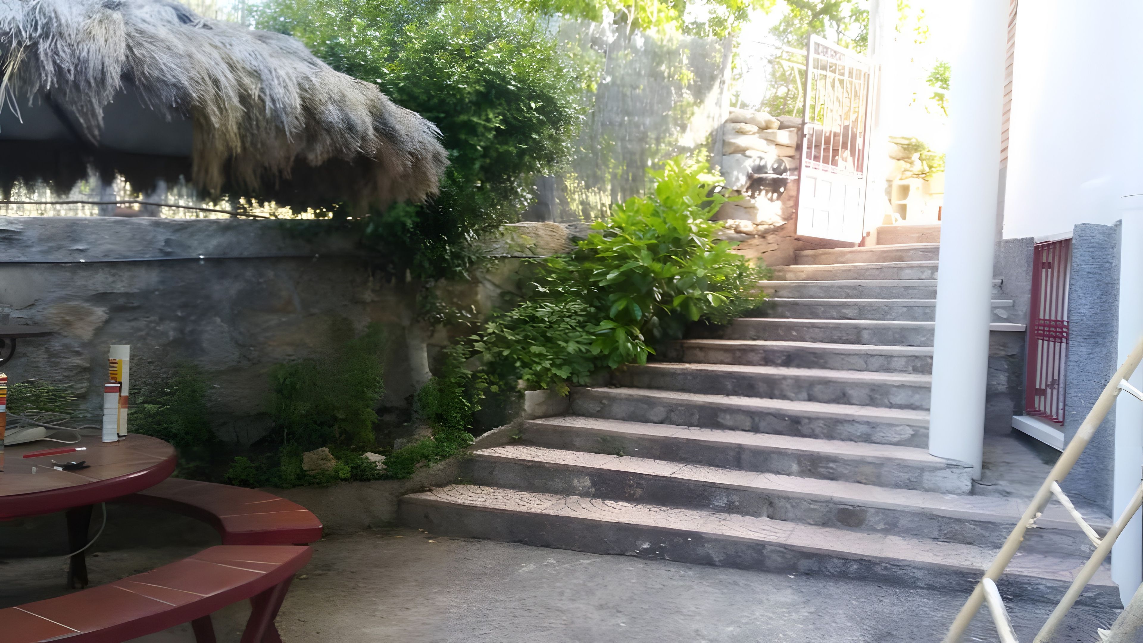 A staircase leading up to a building with a thatched roof structure and a stone wall.