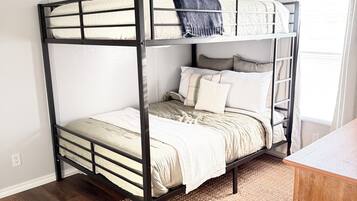 A bunk bed with a wooden frame, a woven rug, and a wooden desk.