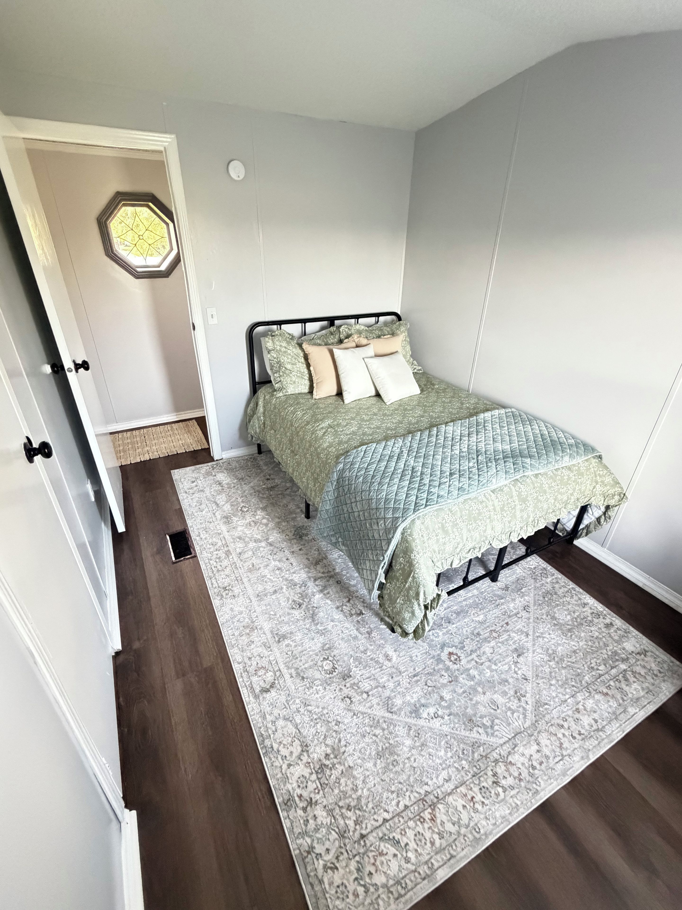 Una camera da letto con un letto, un tappeto e una porta che dà su un'altra stanza.