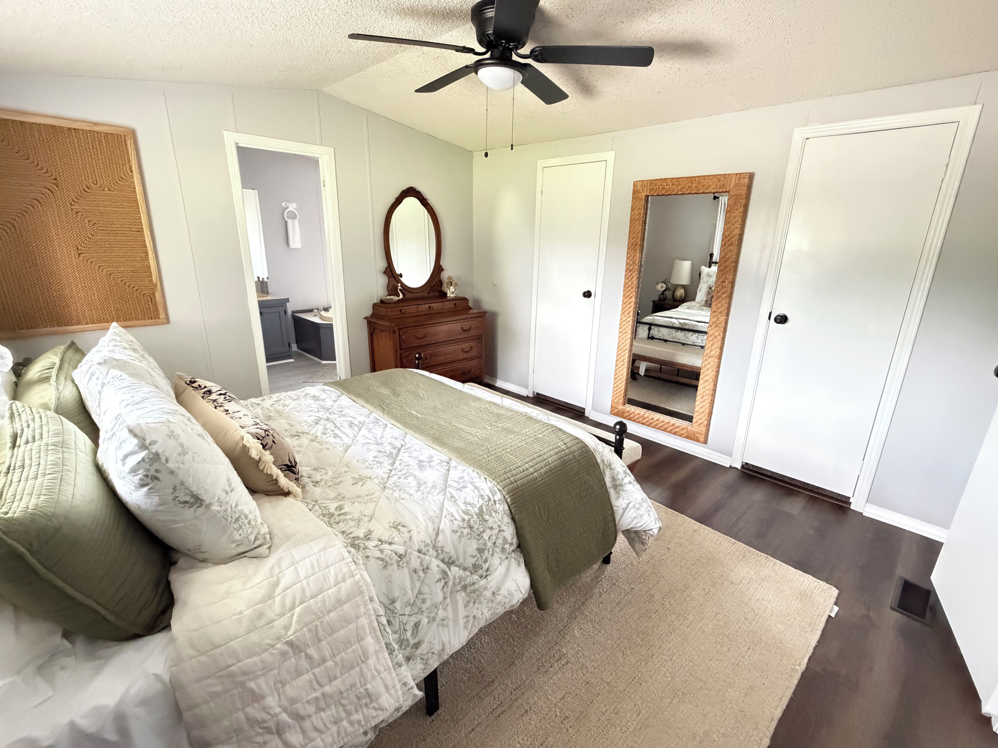 Un dormitorio con cama, cómoda, espejo y ventilador de techo.