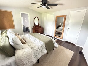 A bedroom with a bed, dresser, mirror, and a ceiling fan.