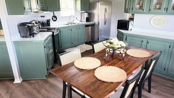 A kitchen with teal cabinets, a wooden dining table with placemats, and a refrigerator.