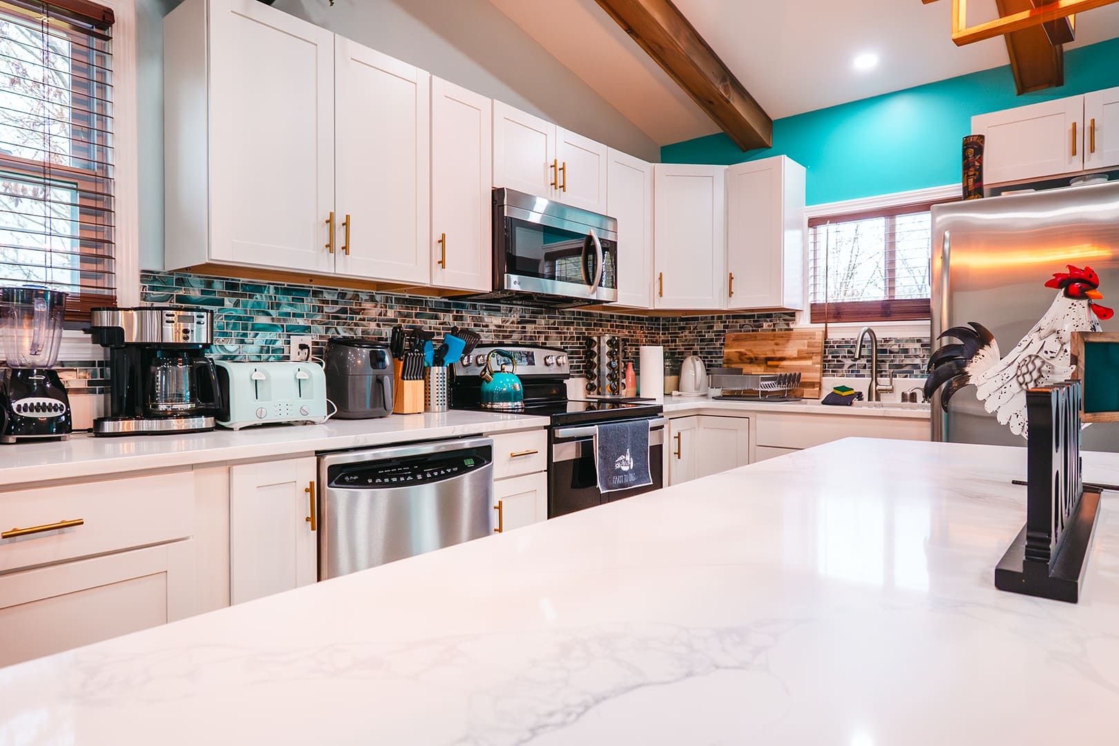 A modern kitchen with white cabinets, a stainless steel dishwasher, a microwave, and a refrigerator.
