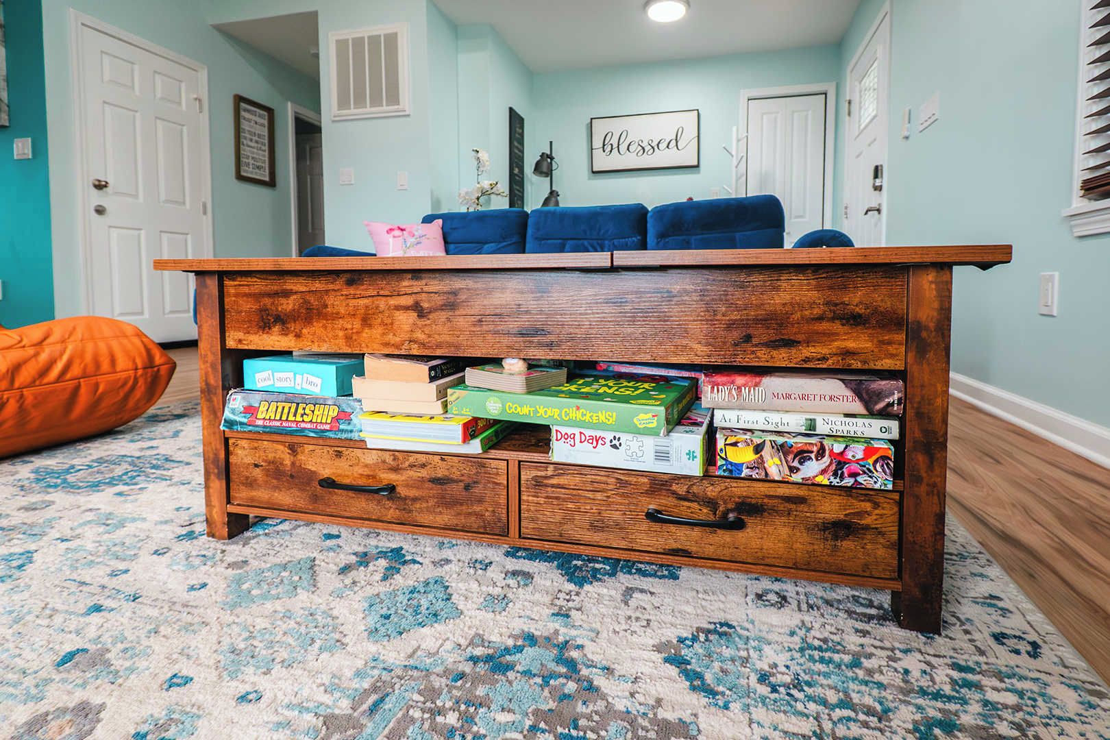A wooden chest of drawers with books and a pink pillow on top.