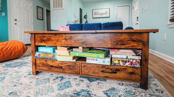 A wooden chest of drawers with books and a pink pillow on top.