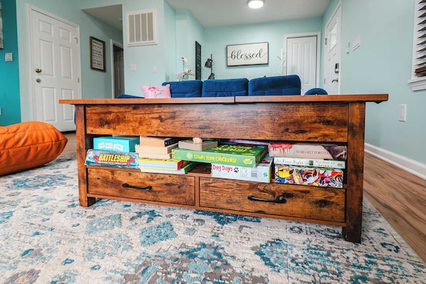 A wooden chest of drawers with books and a pink pillow on top.