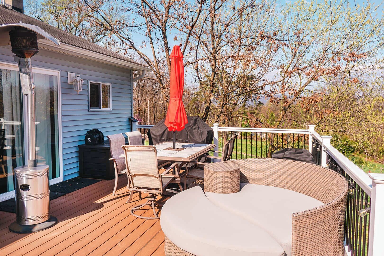 A deck with outdoor furniture, a grill, and a covered table.