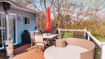 A deck with outdoor furniture, a grill, and a covered table.