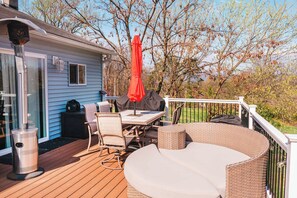 A deck with outdoor furniture, a grill, and a covered table.
