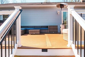 A deck with a railing, a bench, and a trash can.
