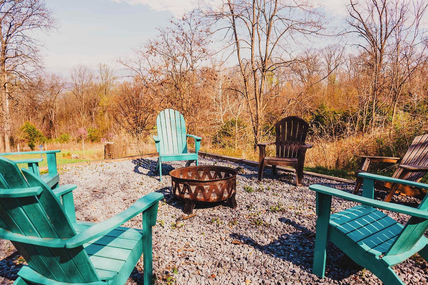 An outdoor seating area with Adirondack chairs and a metal fire pit.