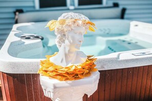 A hot tub with a white marble bust sculpture adorned with golden leaves.