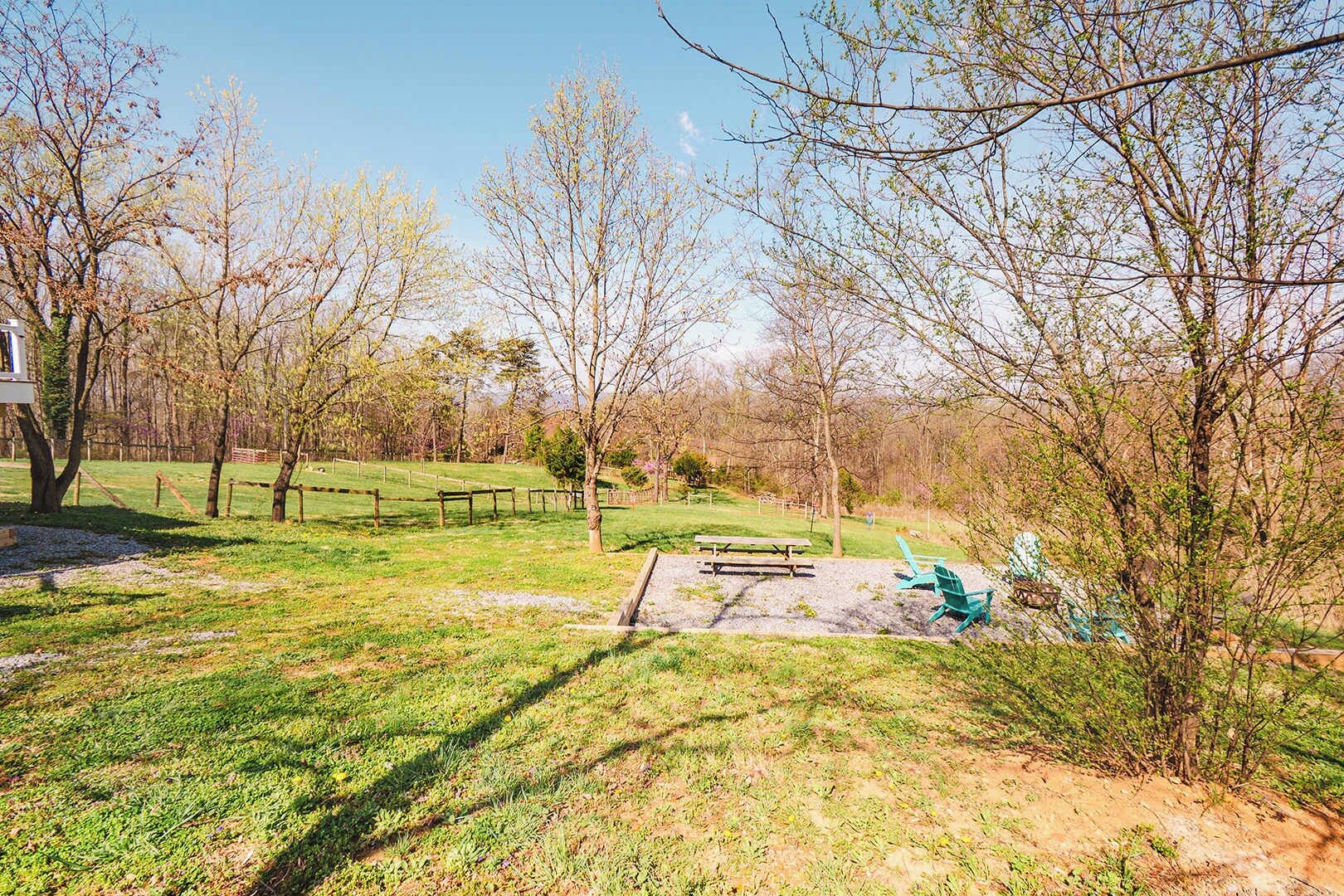 Een park met een picknicktafel, een speeltuin met een glijbaan en een omheind gebied.