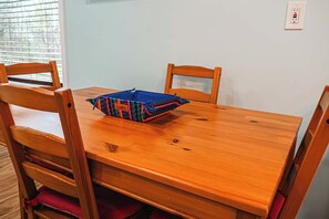 A wooden dining table with a colorful bag on it, surrounded by wooden chairs.