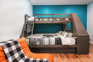 Un lit superposé avec une échelle, une couverture à carreaux et une courtepointe à motifs.