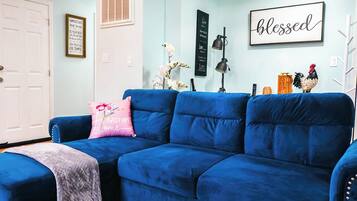A blue sofa with a pink pillow, a white door, and a wall with motivational quotes and a 'blessed' sign.