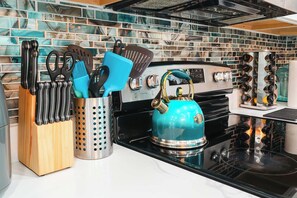 A kitchen with a teal kettle, a knife block, and various utensils.