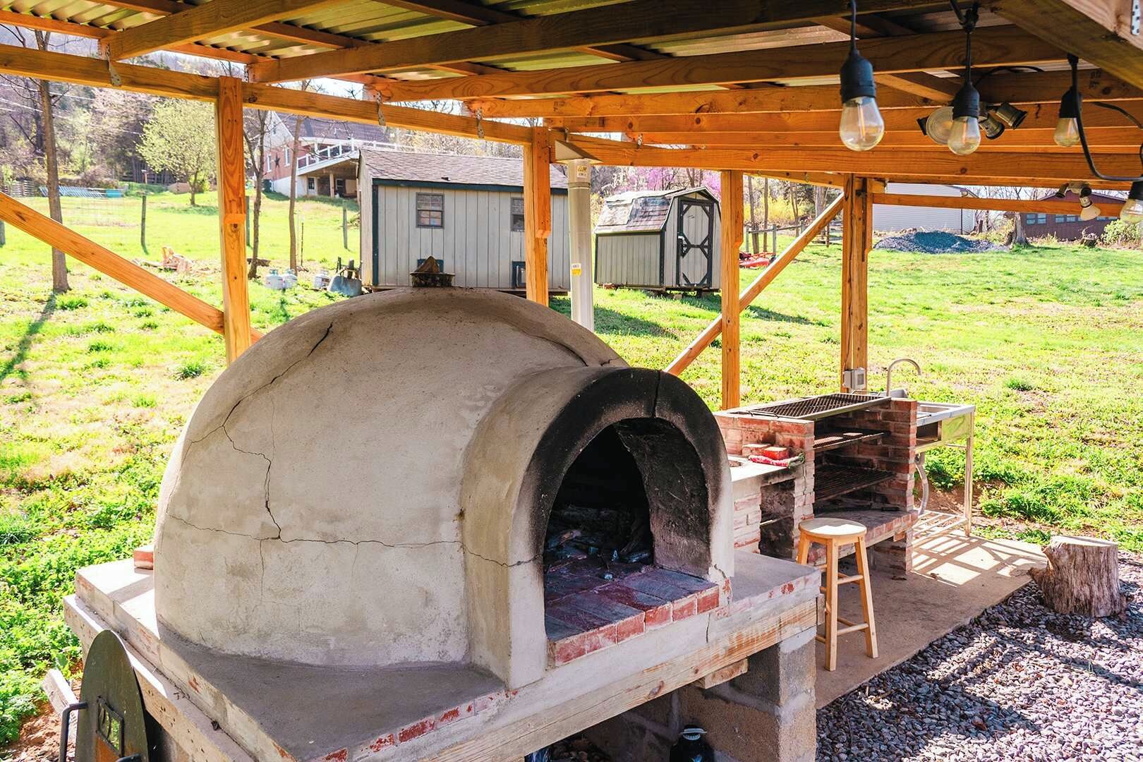 Un four en briques installé à l’extérieur, sous une pergola en bois, avec un barbecue et un espace détente.