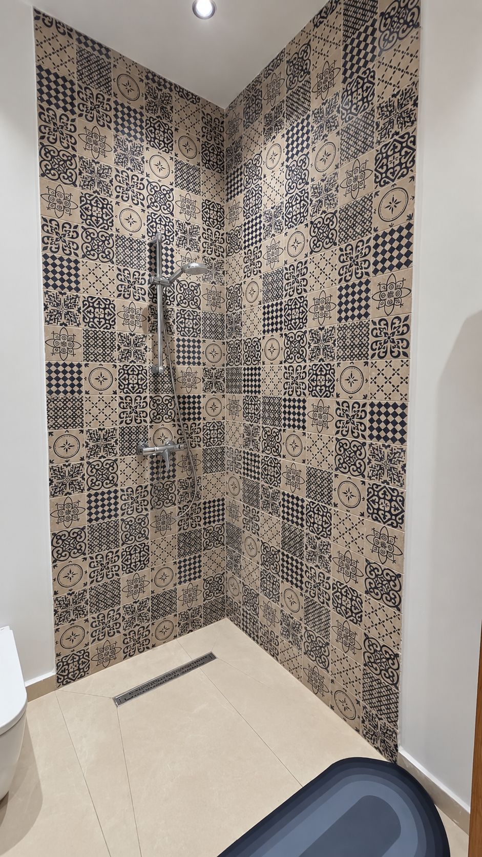 Une salle de bain avec des carreaux décorés, une douche et des toilettes.