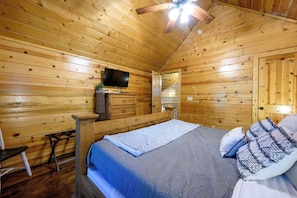 A wooden cabin bedroom with a bed, a television, a dresser, and a bench. - Honey Bear - 1BR Cabin & Hot Tub (Broken Bow)