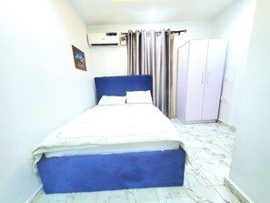 A bedroom with a bed, a wardrobe, a curtain, and an air conditioning unit. - Sophisticated 2-Bedroom Stay | 24Hrs Power & Unlimited Wi-Fi (Agege)