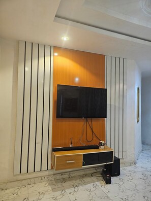 A modern entertainment unit with a flat-screen TV, wooden paneling, and a built-in cabinet with a drawer. - Sophisticated 2-Bedroom Stay | 24Hrs Power & Unlimited Wi-Fi (Agege)