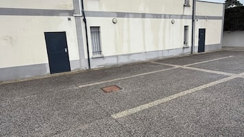 A building with a flat facade, a parking lot, and a gated entrance.