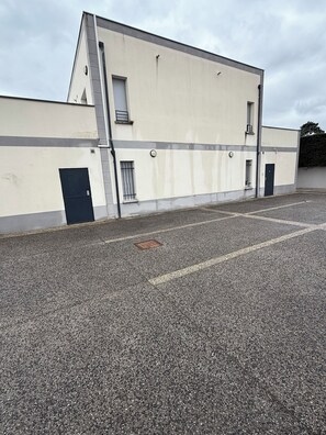 Ein Gebäude mit flacher Fassade, einem Parkplatz und einem verschlossenen Eingang.