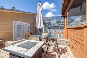 Eine Terrasse mit Tisch und Stühlen, einem Sonnenschirm, einem Pool und einem überdachten Bereich.