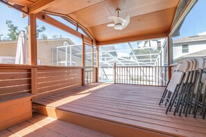A wooden deck with a ceiling fan, a railing, and a view of a residential area. - Cottage on the Bay Pool Home (Tampa)
