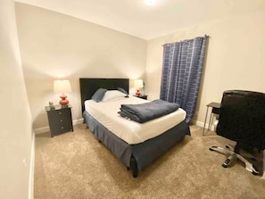 Une chambre à coucher avec un lit, deux tables de chevet, un bureau et une chaise.