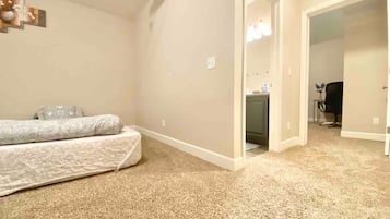 A bedroom with a bed, carpeted floor, and a door leading to a bathroom.