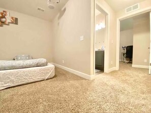 Une chambre à coucher avec un lit, un sol recouvert de moquette et une porte donnant sur une salle de bain.