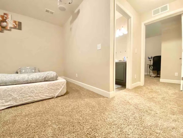 Une chambre à coucher avec un lit, un sol recouvert de moquette et une porte donnant sur une salle de bain.