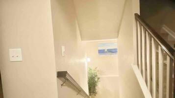 A staircase with a handrail, a wall-mounted light fixture, and a framed picture.