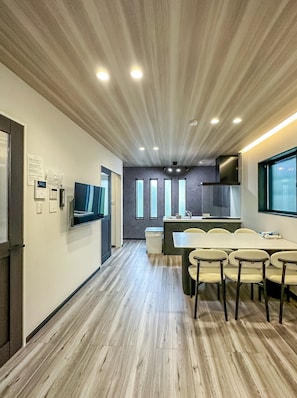 A modern kitchen with a dining area, wooden flooring, and a large window. - HANASTAY HIRO (Osaka)