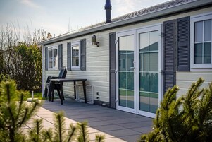 Une maison mobile de plain-pied dotée d’un patio, d’une table avec des chaises et d’une grande porte-fenêtre coulissante.