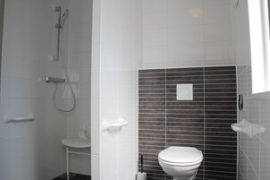 Et badeværelse med bruser, toilet og et håndklædetørrestativ.