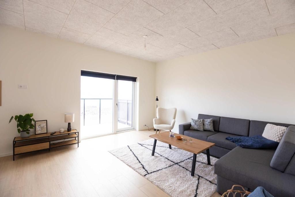 Una sala de estar moderna con un sofá, una mesa de centro y una mesita de noche con lámpara.
