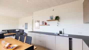 A modern kitchen with a dining area, featuring a wooden table, chairs, and a built-in dishwasher.
