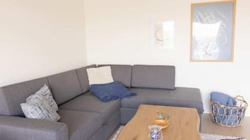 A modern living room with a grey sectional sofa, a wooden coffee table, and a woven basket.